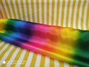 Rainbow satin fabric draped over a yellow and white striped background / Дъгов сатенен плат, драпиран върху фон с жълти и бели райета